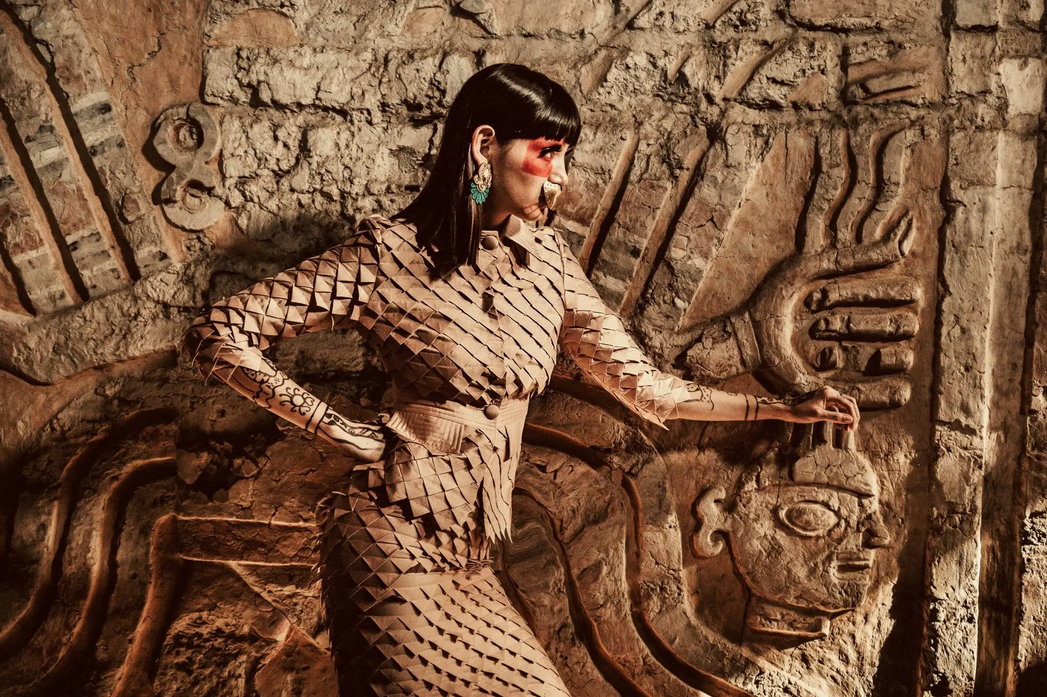 Modelo con diseño inspirado en la Señora de Cao frente a un relieve moche